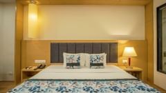 Premium room with double bed, headboard lighting, and wooden furniture at Golden Tulip, Udaipur.