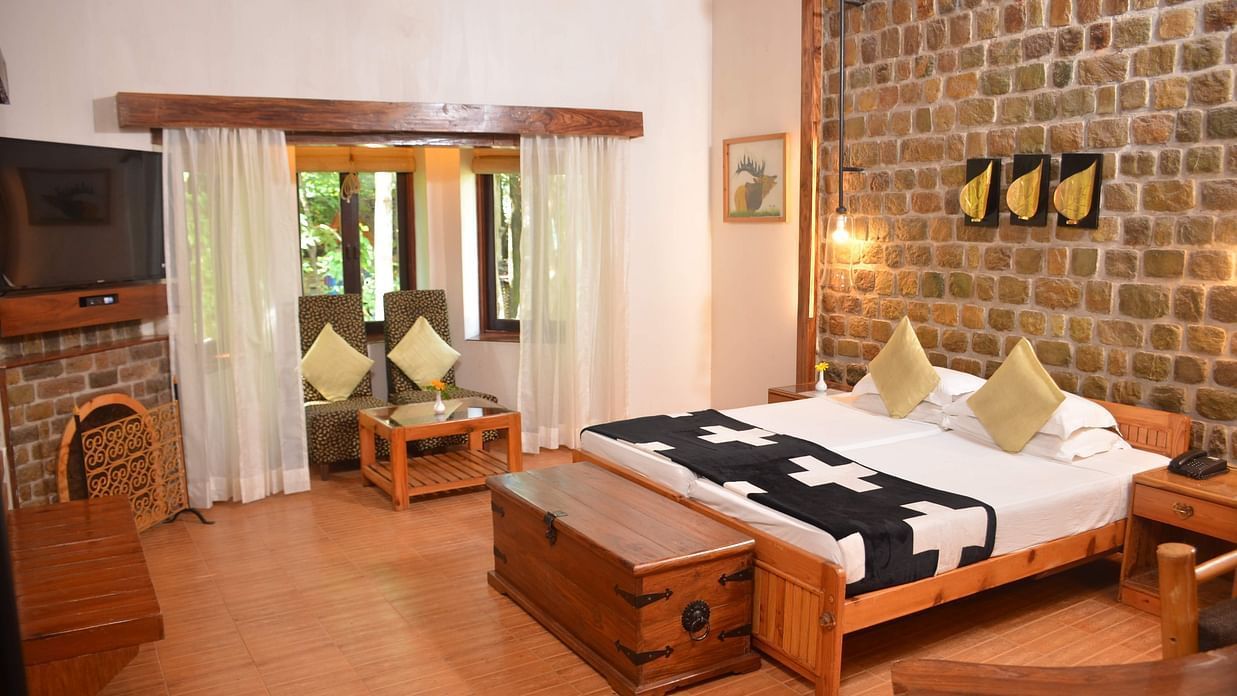 The den corbett resort spa - luxury room with cosy bed and wooden interior2