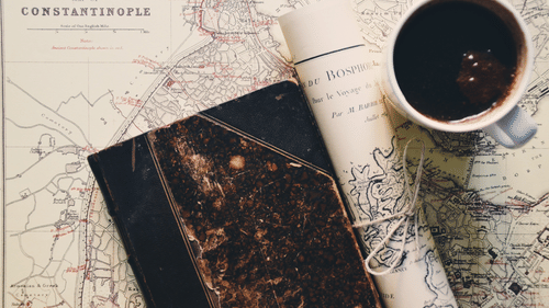 an aerial view of a coffee mug, a folded map and a book kept on a table
