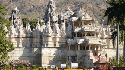 A far away view of a white temple with a hill in the background