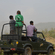 Tourists standing in an open-top safari vehicle observing the landscape in a national park.