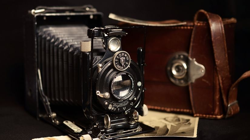 A close up shot of a vintage camera with photographs placed below it.