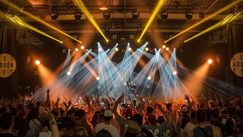 Image of people attending a concert with different laser lights around.