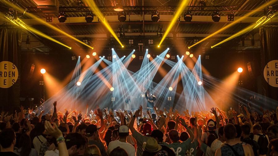 Image of people attending a concert with different laser lights around.