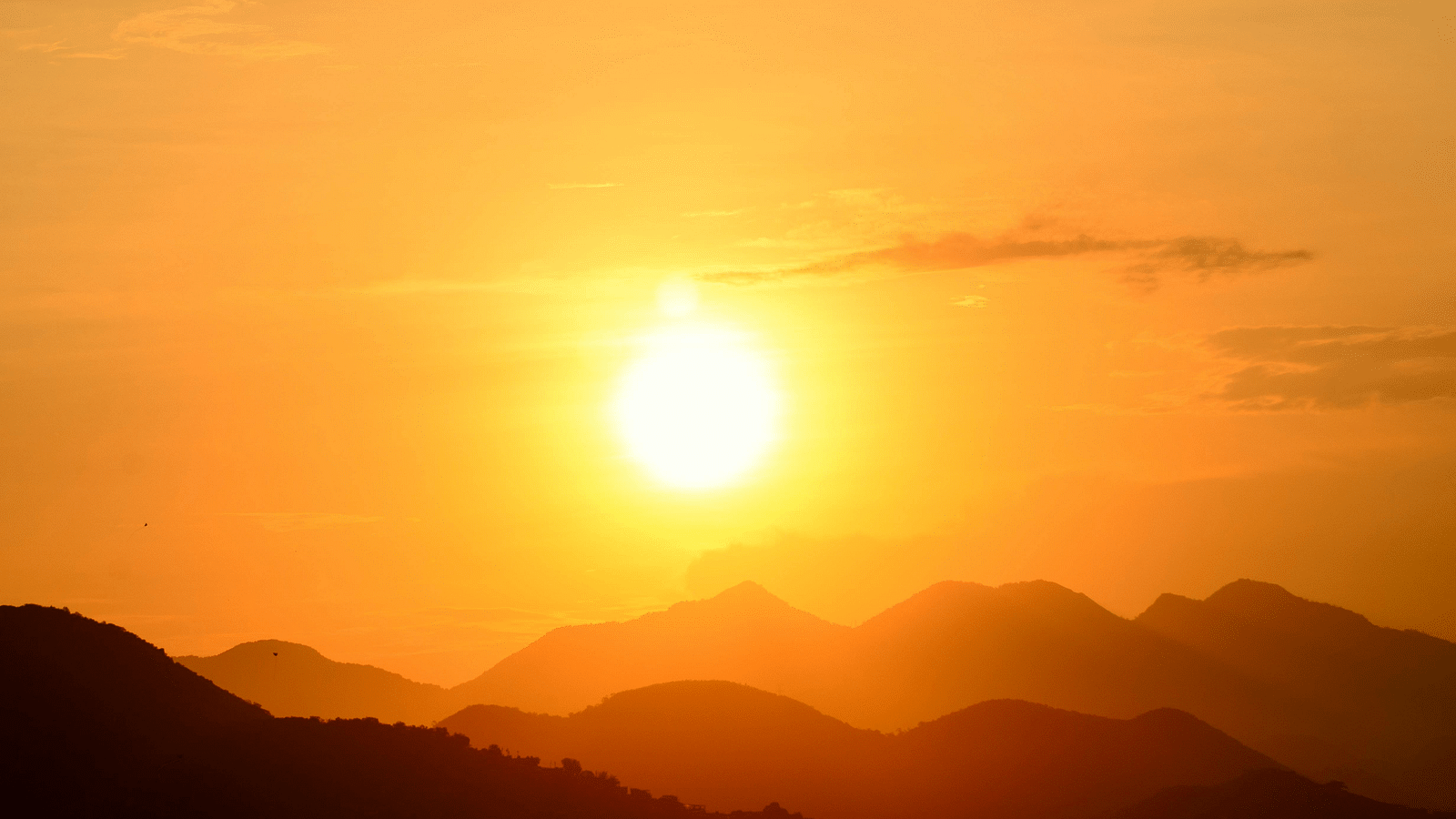 Sun just right over the hills making a silhouette and the light creating a golden hue in the  sky