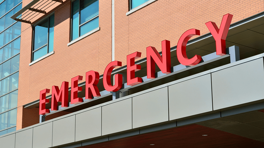 Emergency department entrance of a modern hospital with prominent emergency signage.