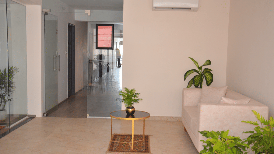 The modern lobby featuring plants along with a white coloured couch and an air-conditioning unit - Lords Eco Inn Belagavi