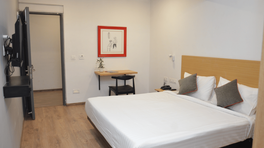 Bedroom with a double bed, bedside table, and a framed picture above it - Lords Eco Inn Belagavi