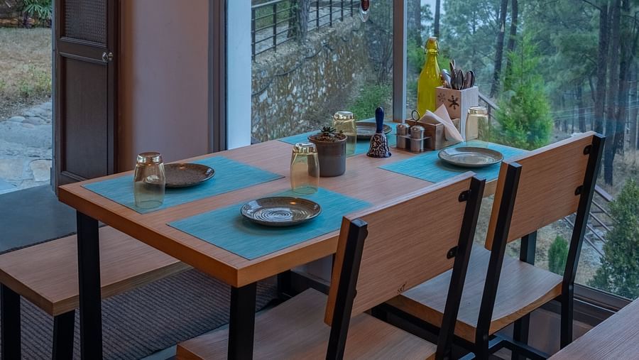 A restaurant with a large glass window beside it, offering a view of the interior dining area at BluSalzz Escapade Resort, Lansdowne
