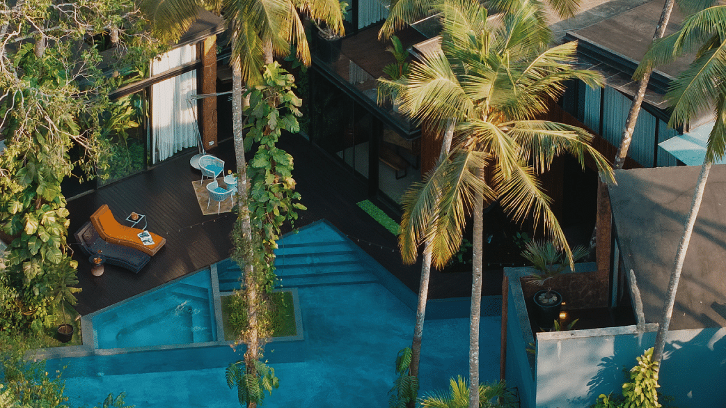 Aerial view of a serene tropical villa with a private pool surrounded by lush palm trees