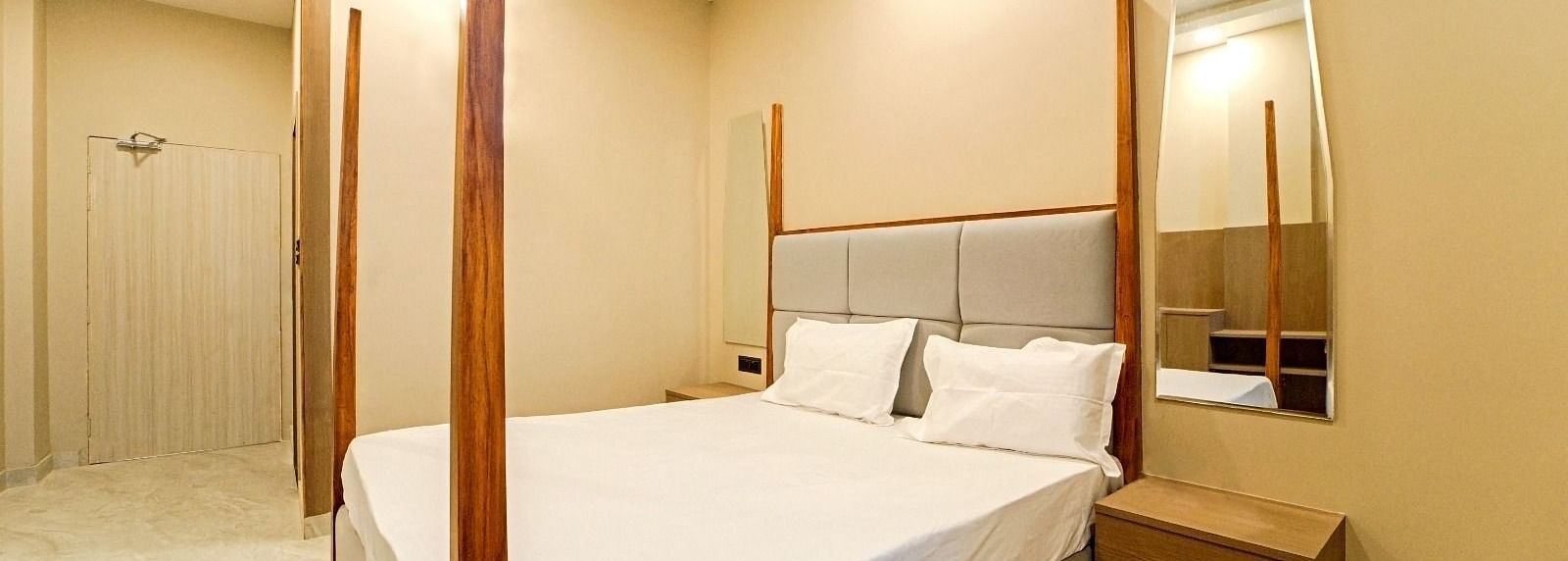 A bedroom at Grassfield Riveria Resort, Jaipur, with a four-poster bed, minimalist decor, and a private bathroom.