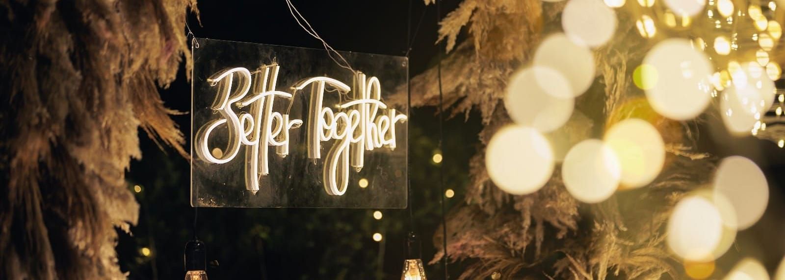 A lighted sign that reads 'Better Together', surrounded by fairy lights and pampas grass decorations Valley by Grassfield.