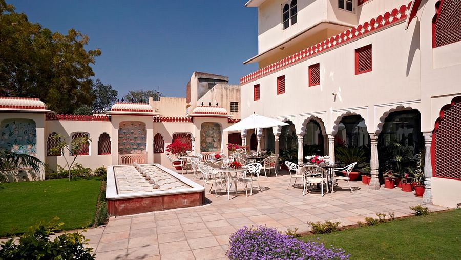 Seating arrangments in an open air setting with a fountain next to grass - Mandawa Haveli Jaipur