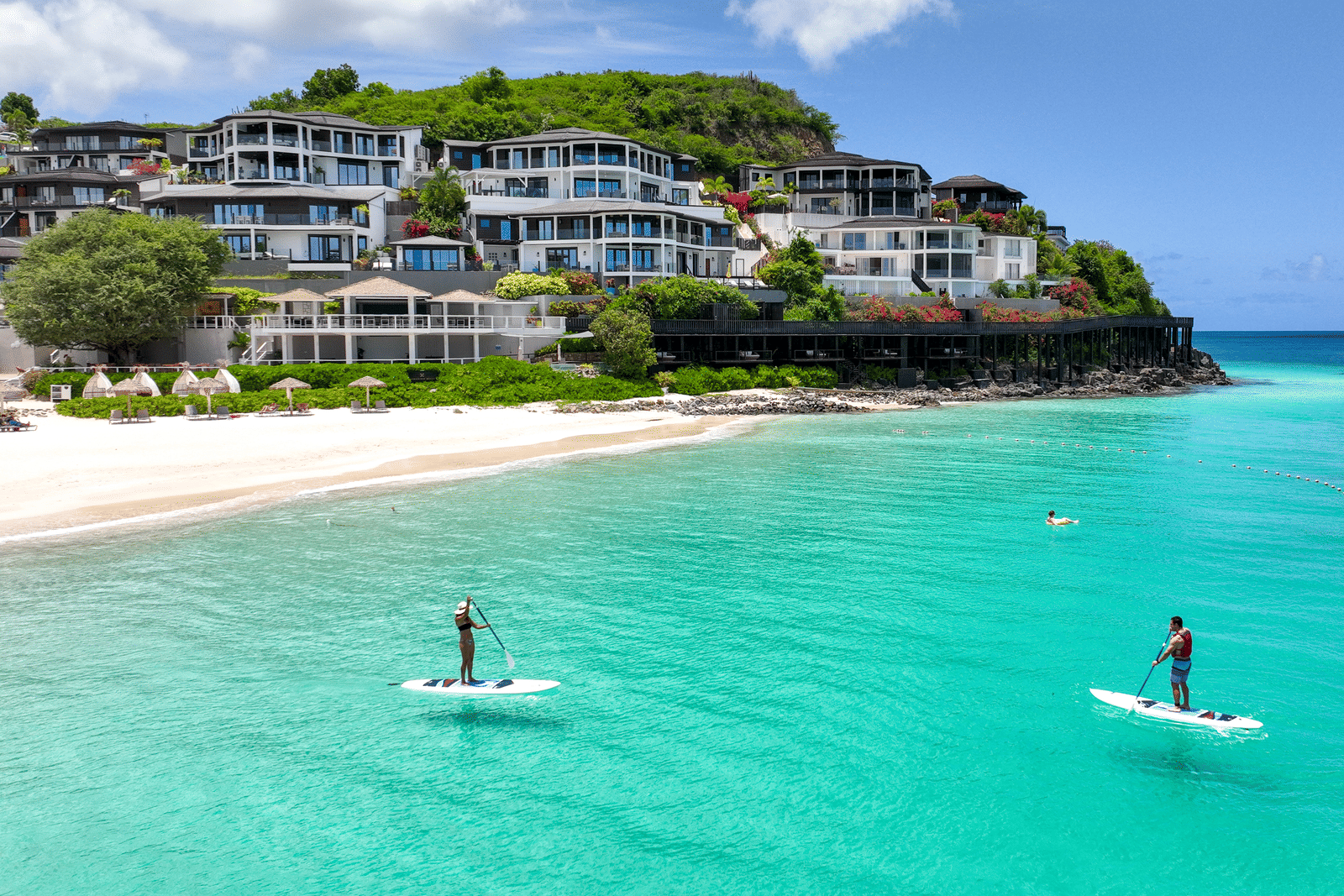 Guests paddleboarding on turquoise waters near Tamarind Hills Resort, Antigua.