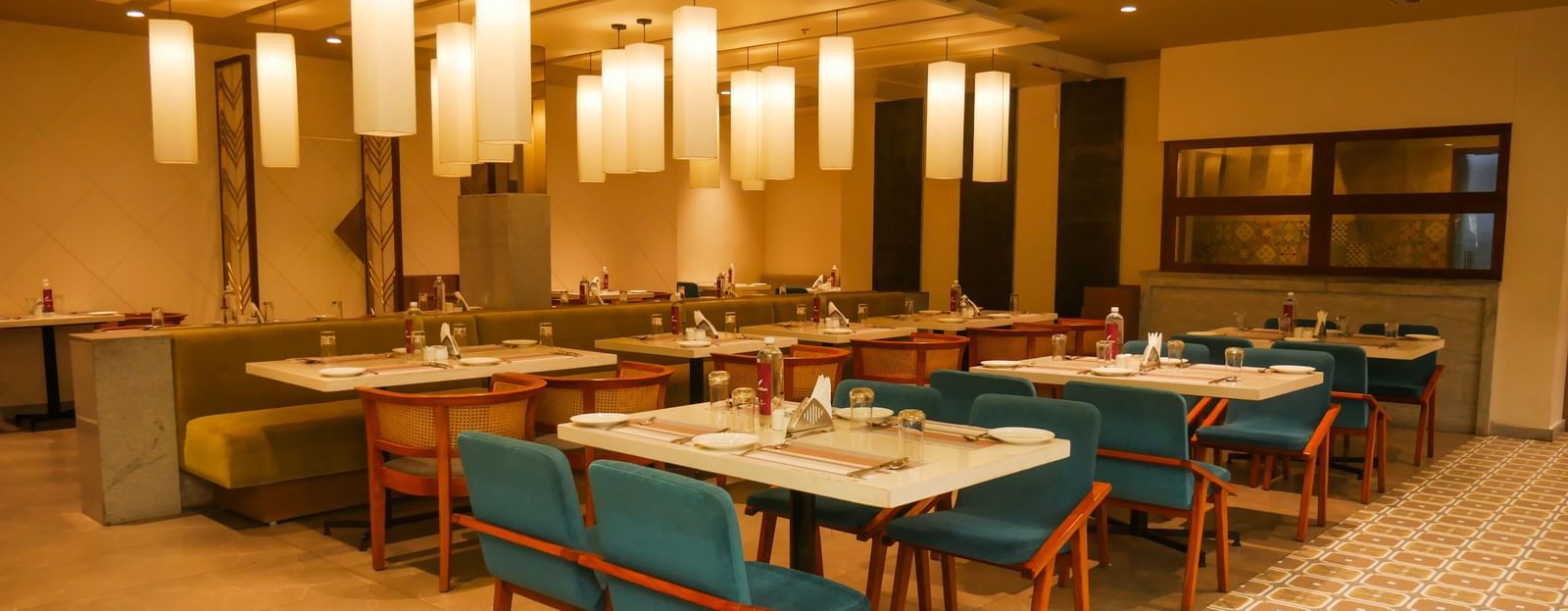 A brightly lit restaurant interior with tables set for dining and a buffet counter in the background at Shilton Dee Cee.