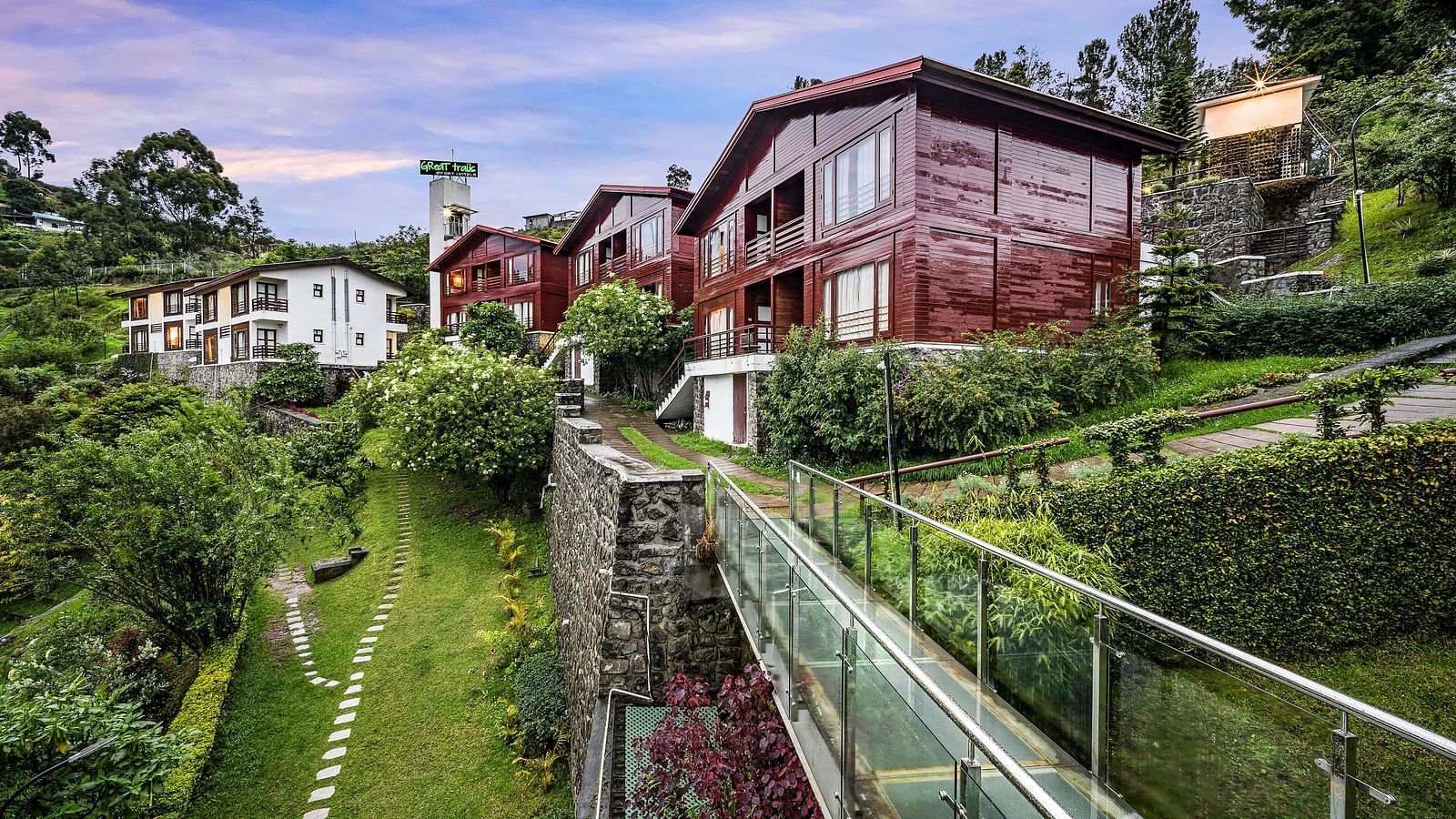 An image of the exterior view with lush greenery and floral arrangement like a garden with the hotel building in the background - GReaT Trails Kodaikanal By GRT Hotels