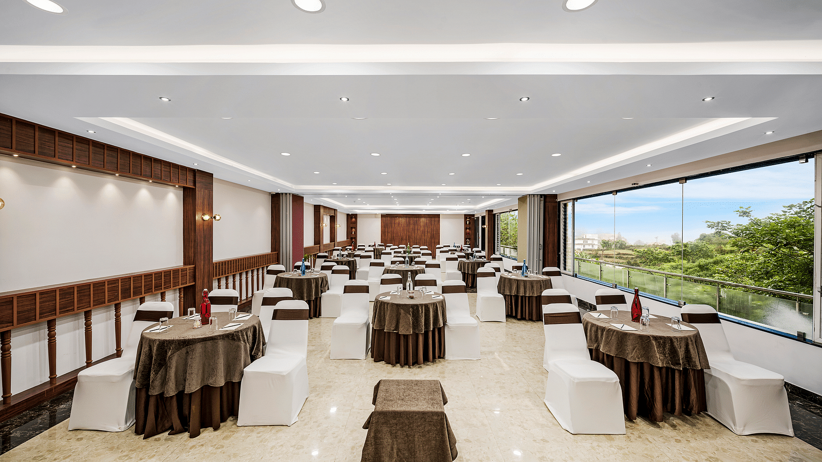 An image of a banquet space which is brightly lit with seating arrangement - GReaT Trails Kodaikanal By GRT Hotels