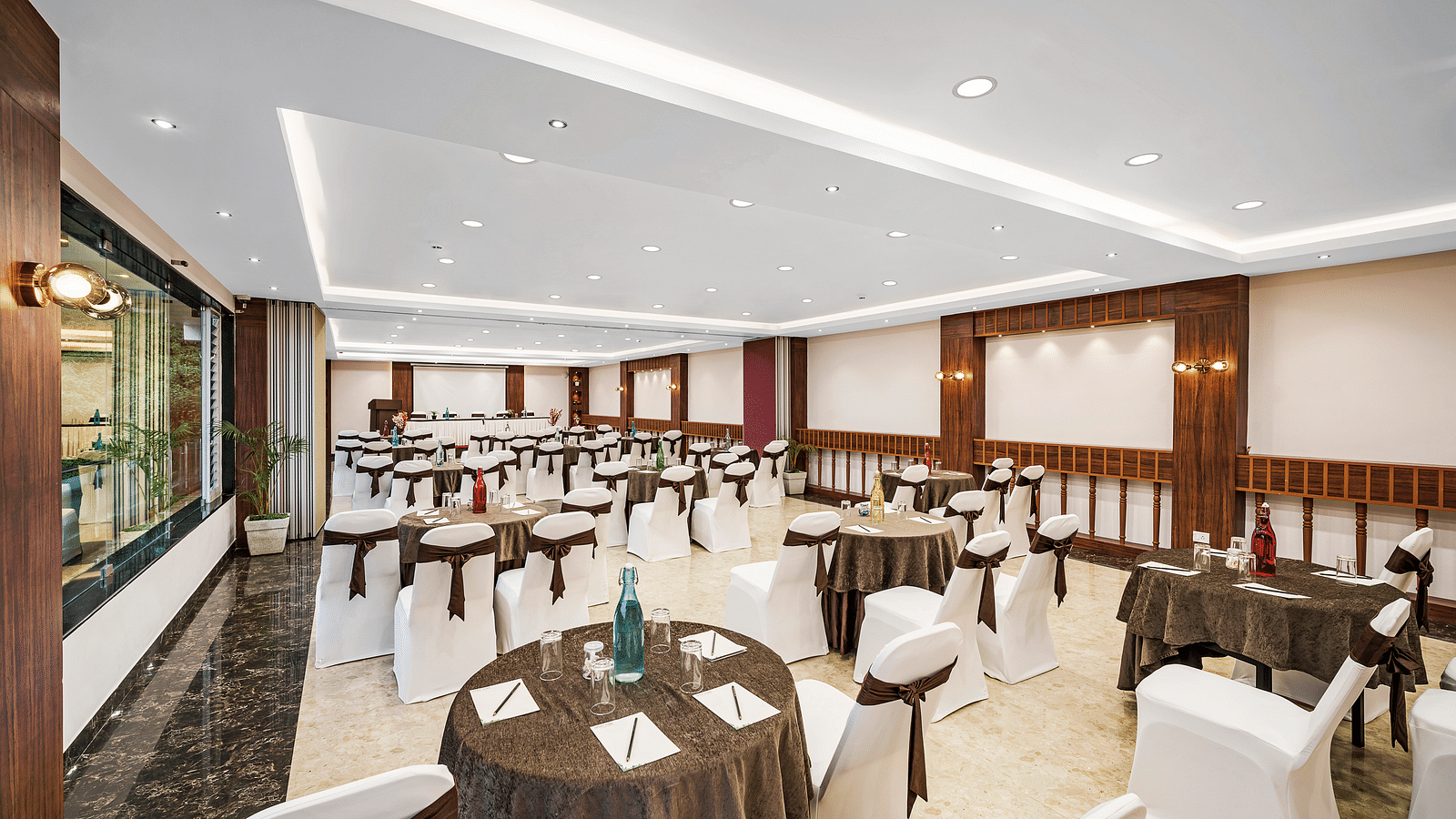An image of a banquet space which is brightly lit with seating arrangement - GReaT Trails Kodaikanal By GRT Hotels