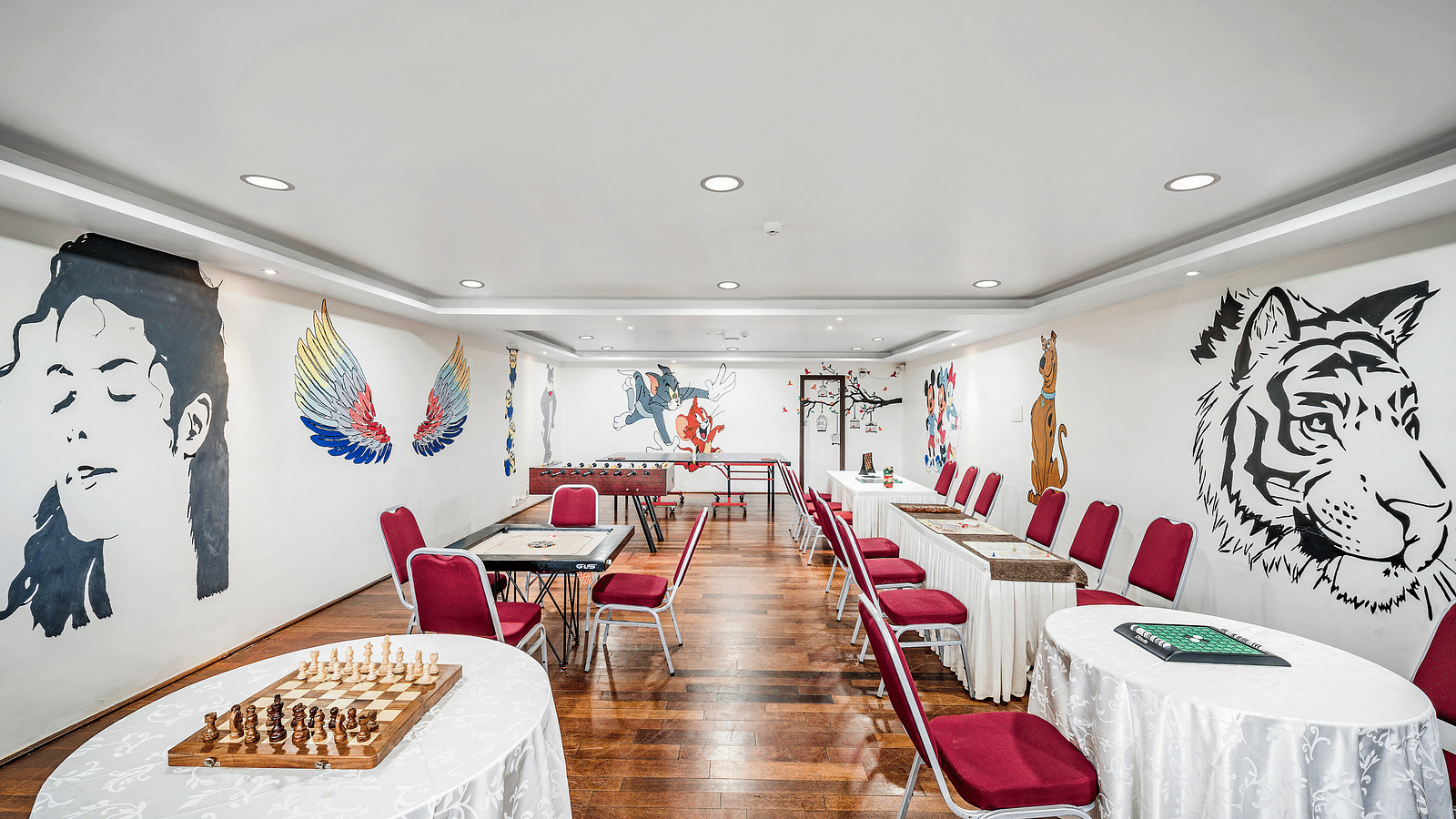 An image of a restaurant with the seating arrangement, and wall paintings - GReaT Trails Kodaikanal By GRT Hotels