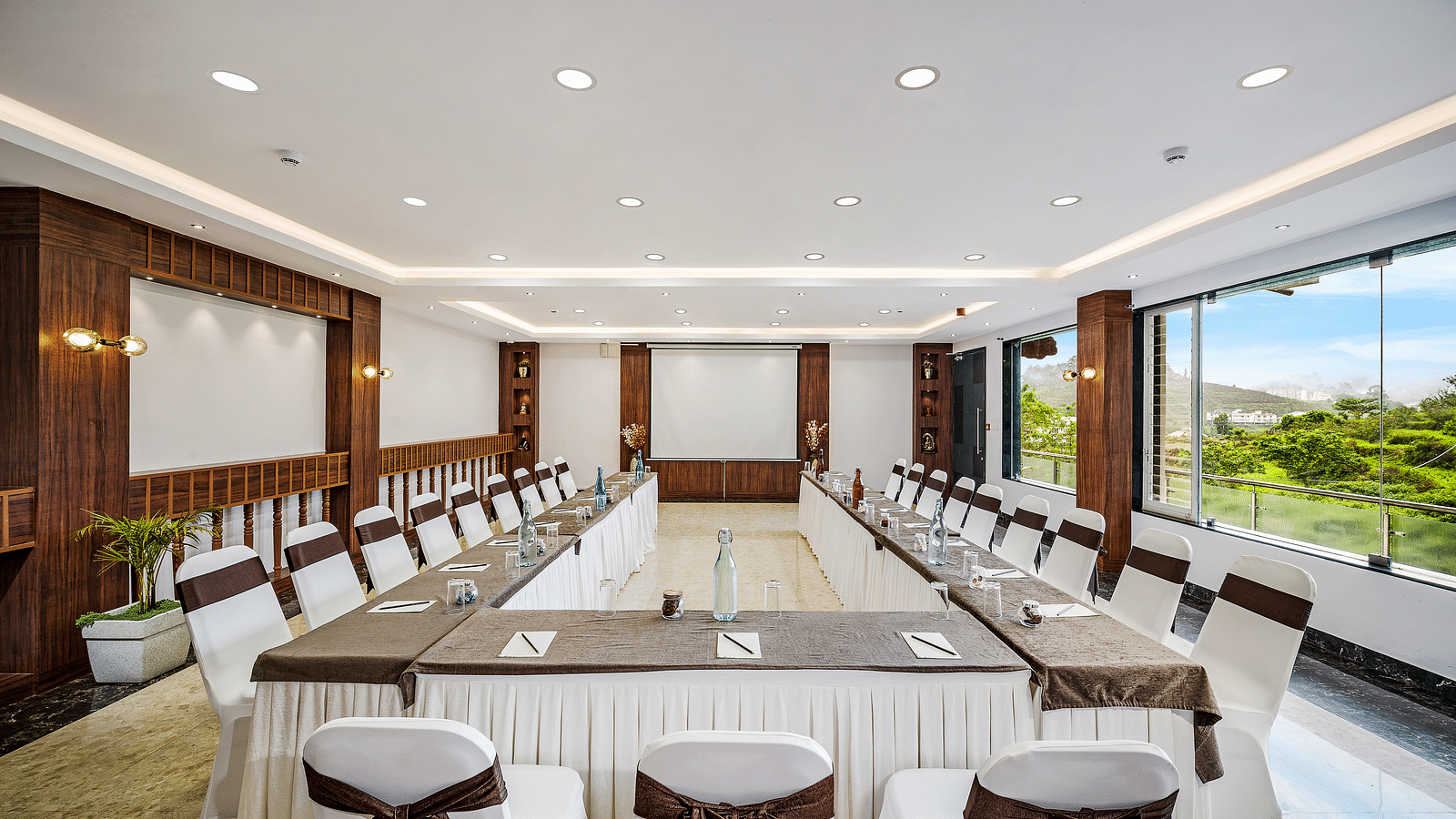 An image of a banquet space which is brightly lit with seating arrangement - GReaT Trails Kodaikanal By GRT Hotels