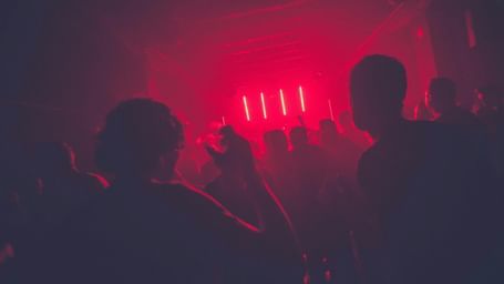 A view from inside a club with red tint and hues and silhouettes of people for the perfect Nightlife in Jamaica.