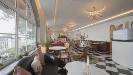 Stylish cafe interior with natural lighting, white tables, and cushioned seating - Mayfair Cafe & Suites, Dalhousie