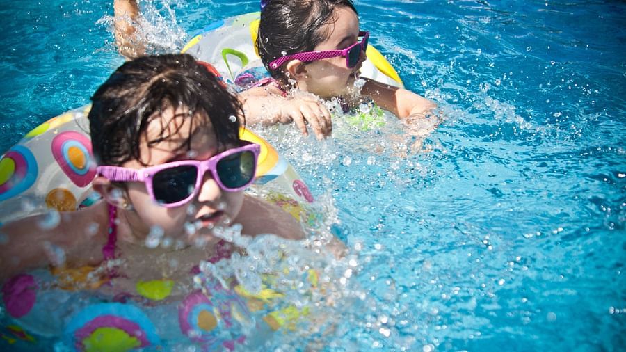 An image of two toddlers with sunglasses on in a swimming pool