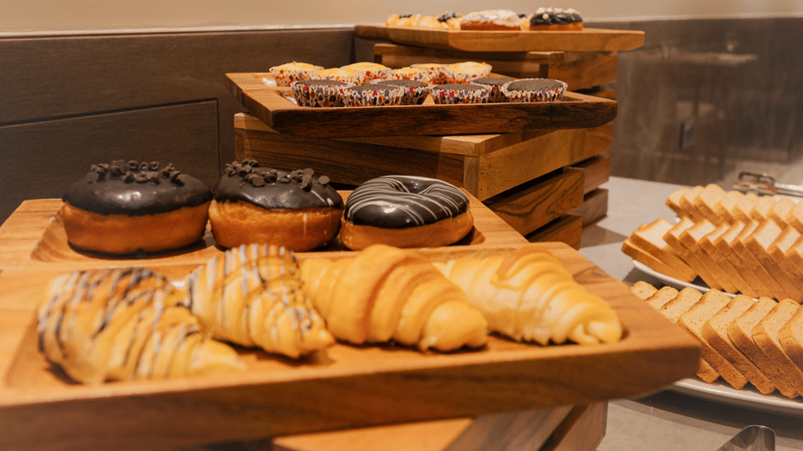 A selection of fresh chocolate donuts and croissants displayed on wooden tiers at the breakfast buffet in Ananta Express, Katra.