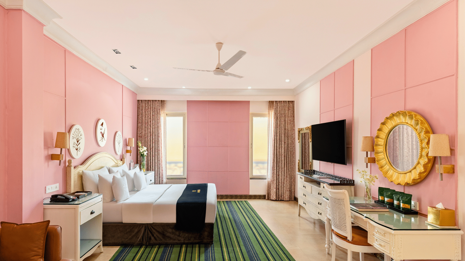 Family room with a king bed, a writing desk, an armchair, a wall-mounted television and curtained windows at MAYFAIR Palm Beach Resort, Gopalpur-on-Sea.