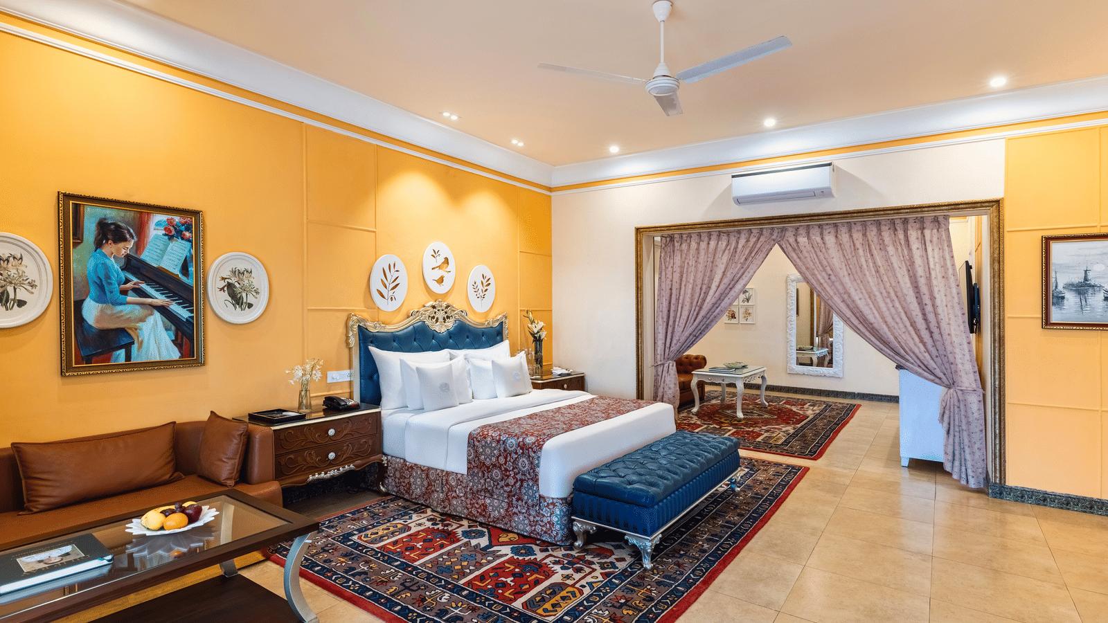 Family suite with a king bed, a seating area, a sofa, a coffee table and an adjoining room through an archway at MAYFAIR Palm Beach Resort, Gopalpur-on-Sea.