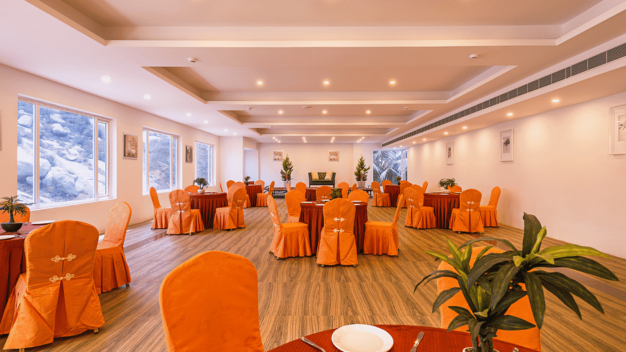 Another view of the spacious dining hall with orange chair covers and round tables set for a meal - TGI Grand Fortuna, Hosur