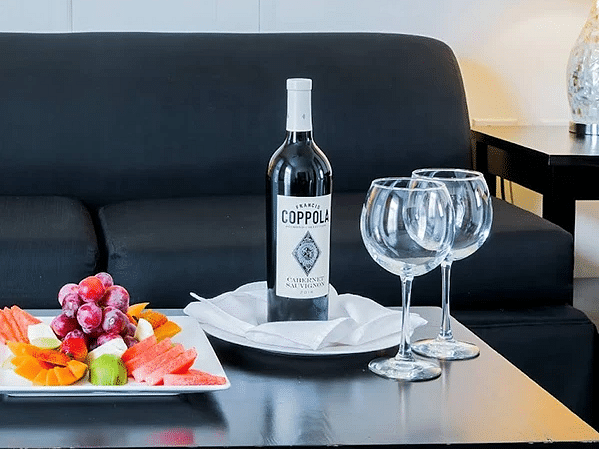 A close up shot of a wine bottle with wine glasses and a delicious Jamaican dish placed on a table in our suite in Jamaica - S Hotel Kingston, Jamaica
