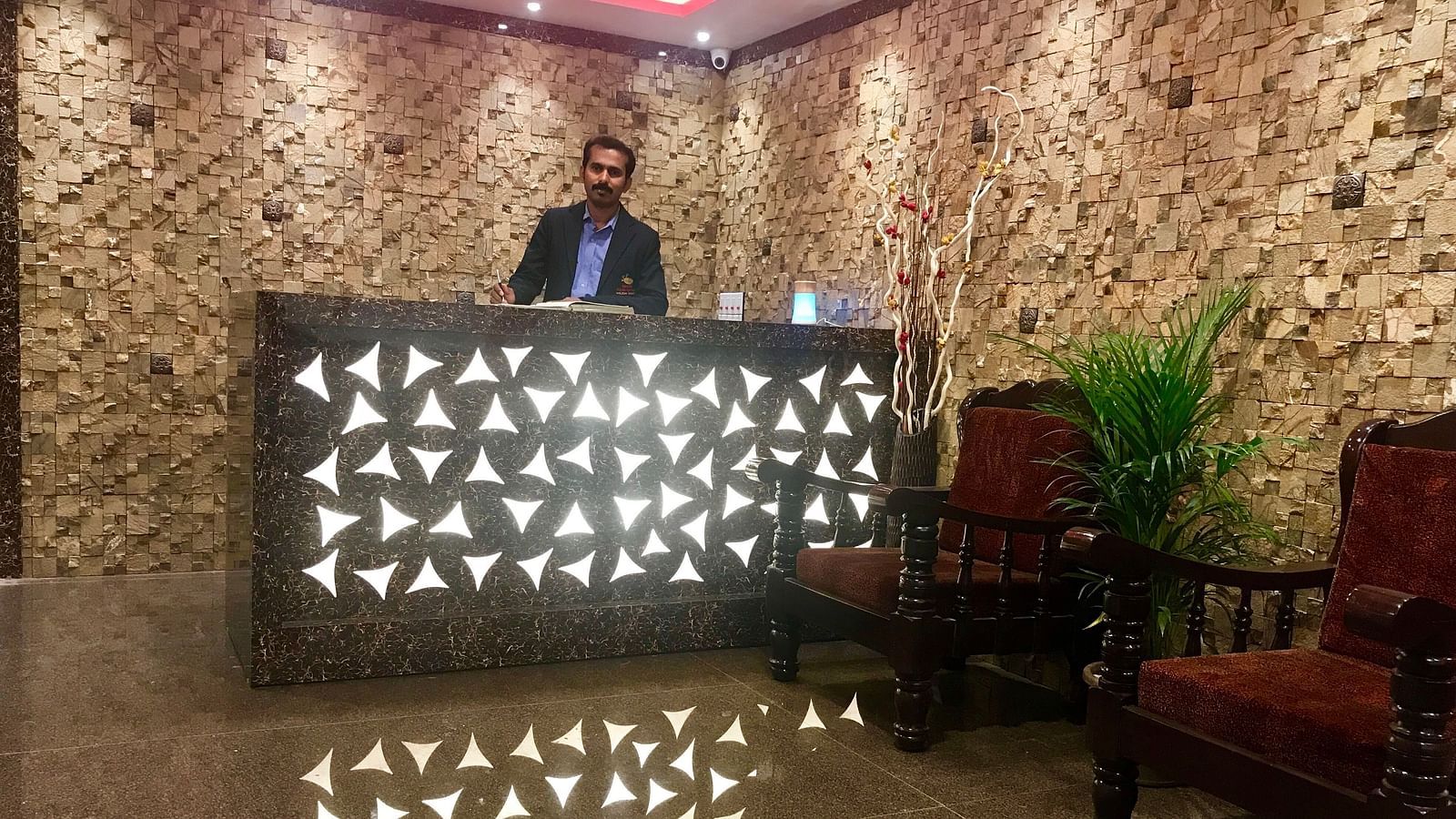 Image of a man standing behind a counter table at Parampara Residency, Kushalnagar..