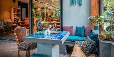 Outdoor seating area at Karma Chalets with cushioned benches, chairs, and plants under a wooden canopy.