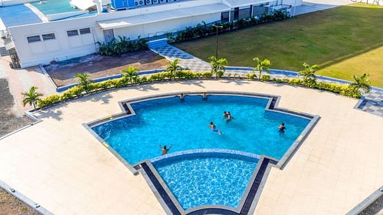 swimming pool as seen from above with a building in the background - The Orchid Hotel, Jamnagar