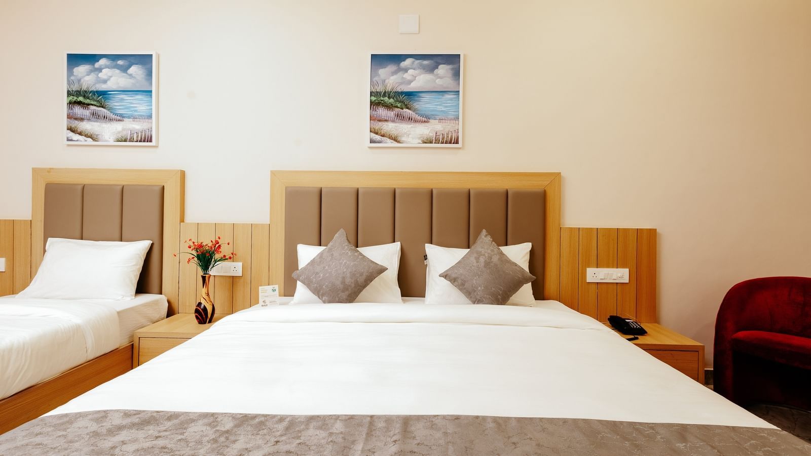 Close up shot of a double bed of the Pride Room at Daksh The Grand Gowardhan, Dwarka, showcasing its clean linen and a decorative art piece hung above it.