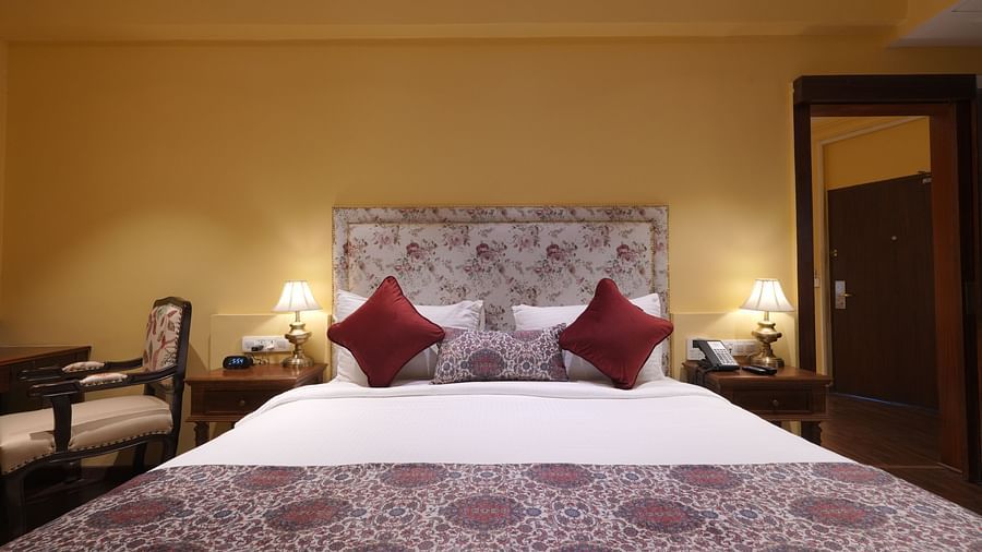 Front view of the double bed and side tables beside it in the Suite Cottage Room at The Garden Ananta Elite Rajkot 5
