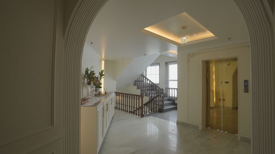 Well-lit corridor leading to a staircase with elegant arches and minimalist design - Mayfair Cafe & Suites, Dalhousie
