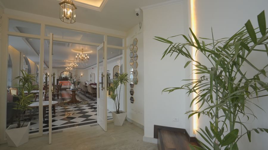 Glass entrance with ambient evening lighting and potted plants - Mayfair Cafe & Suites, Dalhousie