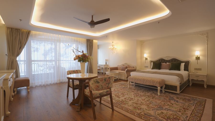 Spacious suite with queen size bed, wooden flooring, and warm ambient lighting - Mayfair Cafe & Suites, Dalhousie