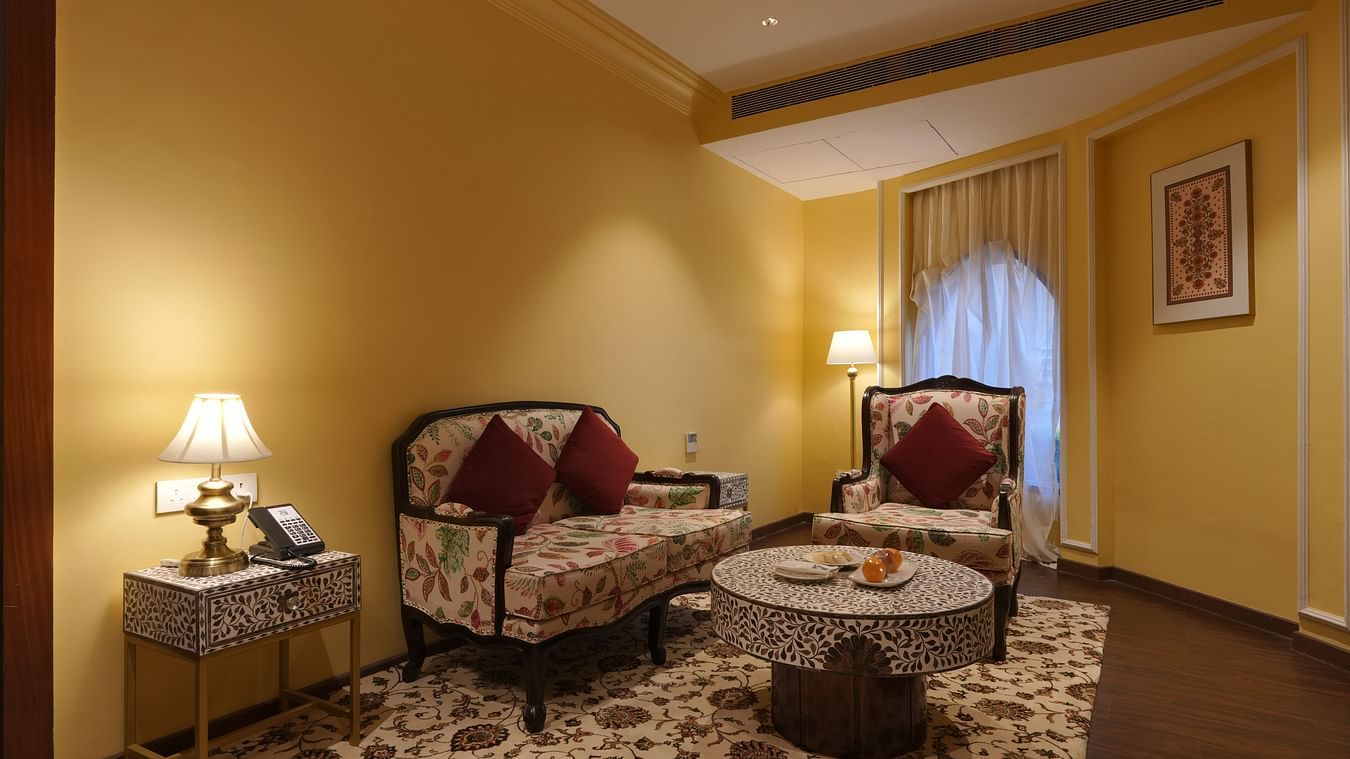 Front view of the royal seating, two sofas and a small side table in the Suite Cottage Room at The Garden Ananta Elite Rajkot 3