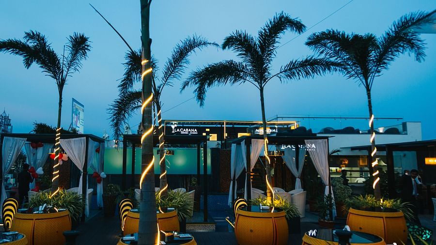 chairs with tables placed across a space with decorated trees in between them - Hotel Park Elanza, Chennai