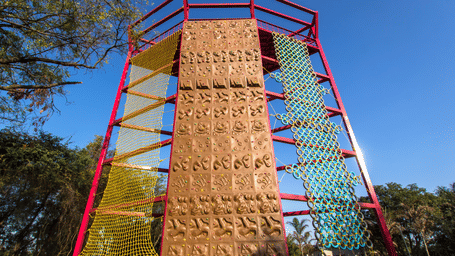 A large climbing wall structure stands outdoors under a blue sky - District Gravity Adventure Park, Hyderabad