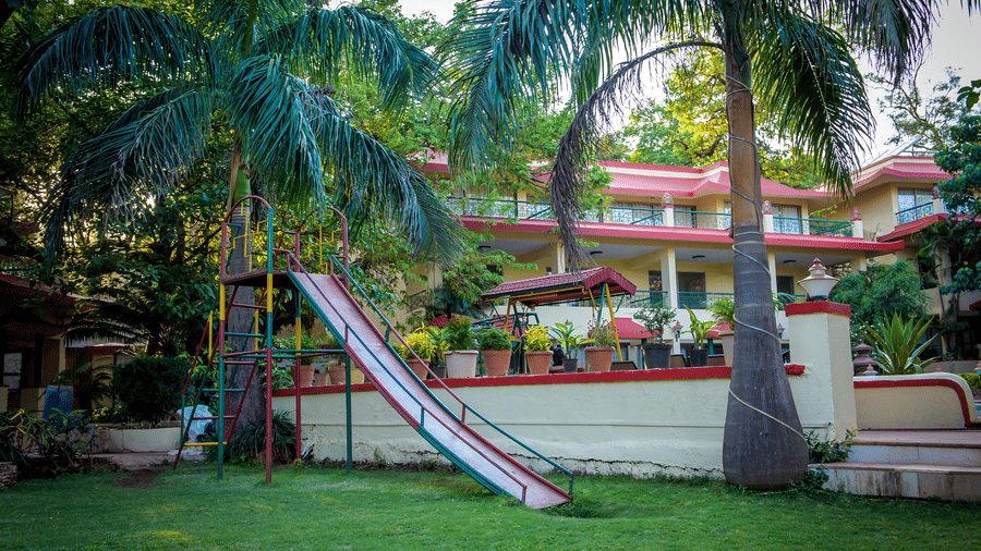 A play area for kids with a slide and surrounded by palm trees and the buildings.