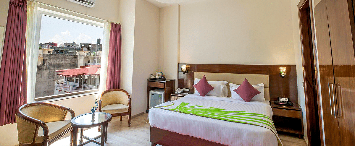 Full view shot of the Deluxe room featuring a double bed along with beautiful city views from the window at Regenta Inn DLS.