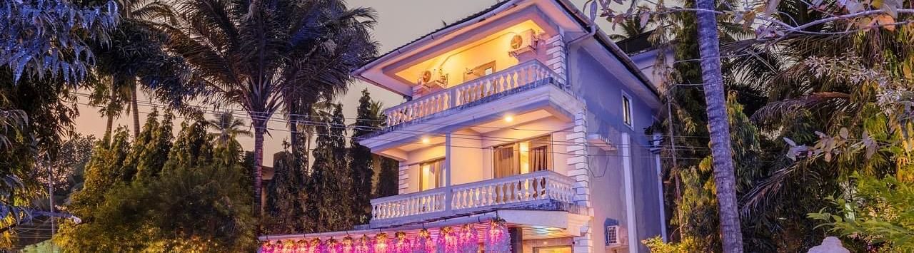 Facade of Calux Joia Do Mar Resort, Goa with tress beside it.