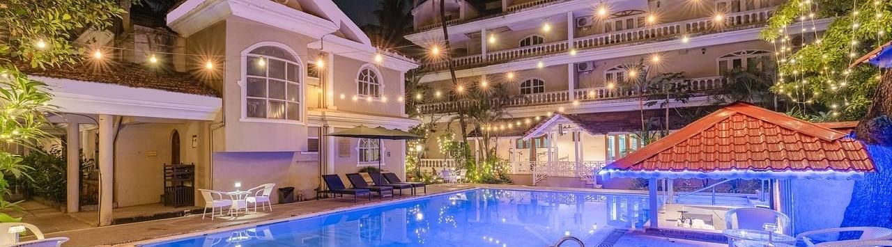 Facade of Calux Joia Do Mar Resort, Goa with a swimming pool in front.