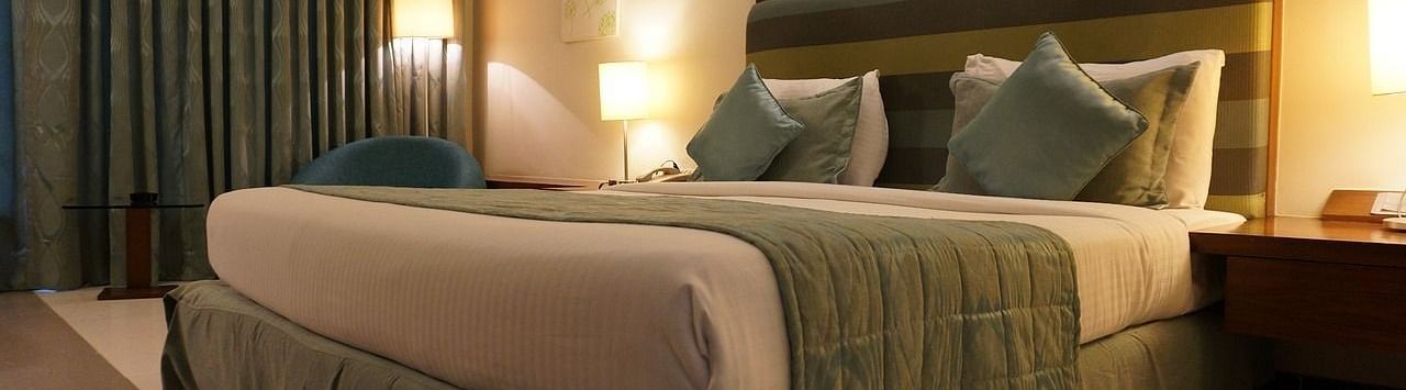 A hotel room featuring a comfortable bed, a lamp and a chair.