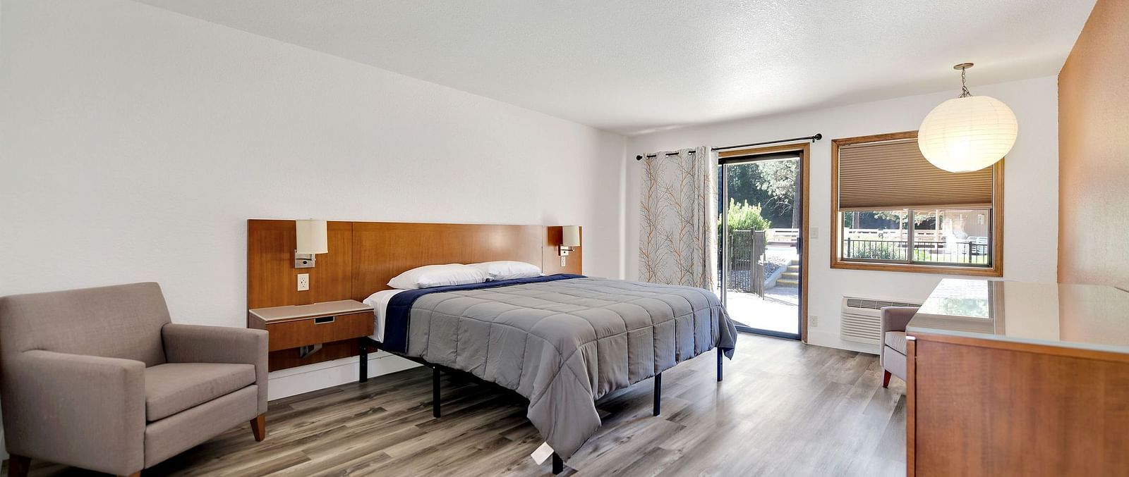 A view of a room at Amador Hotel with a double bed and a sofa chair.