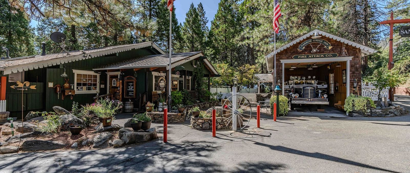 Exterior of a few wooden cabins at Narrow Gauge Inn with trees in the backdrop on a clear, blue day.